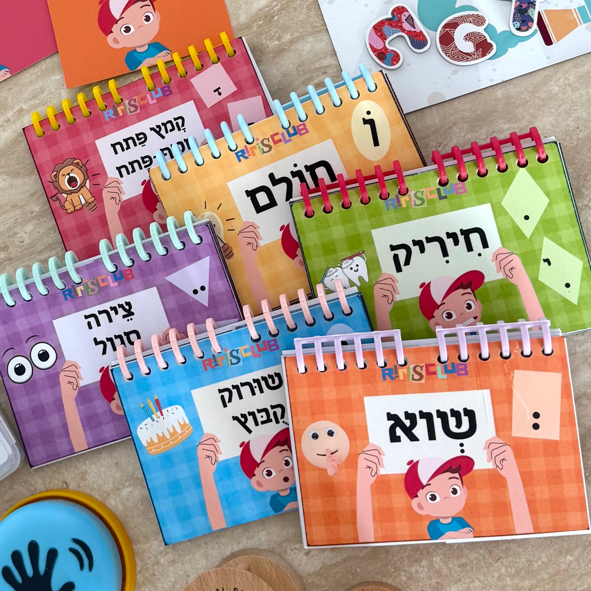 Set of colorful children's educational books with Hebrew text on a wooden surface